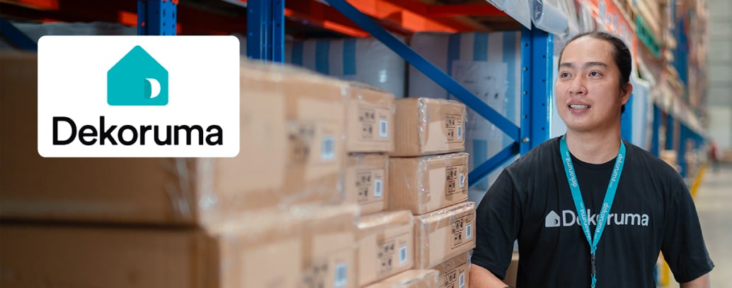 A person wearing black shirt surrounded by package boxes in a warehouse