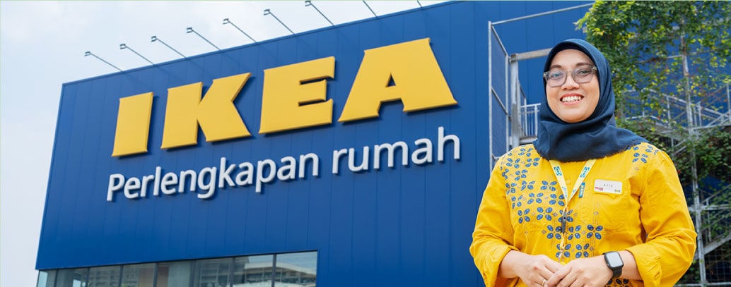 Seorang wanita menggunakan baju bewarna kuning sedang berdiri didepan toko IKEA