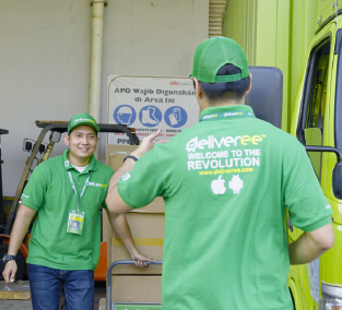 Dua orang supir truk menggunakan baju hijau sedang berbicara satu sama lain