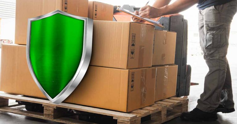 seorang pekerja logistik yang sedang menulis di sebuah clipboard dengan kotak-kotak paket yang memiliki perisai hijau besar di depannya, menandakan asuransi.