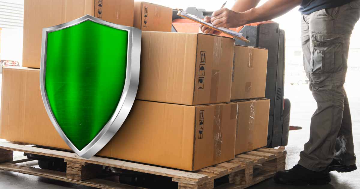 seorang pekerja logistik yang sedang menulis di sebuah clipboard dengan kotak-kotak paket yang memiliki perisai hijau besar di depannya, menandakan asuransi.