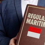 Buku coklat bertuliskan regulasi maritim dengan bendera indonesia
