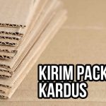 Tumpukan kardus bergelombang dengan tulisan "Kirim Packaging Kardus".
