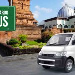 Mobil Deliveree di depan landmark Kudus dengan papan petunjuk 'Ekspedisi Cargo Kudus'.