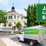 Truk Deliveree sedang melintas di depan bangunan bersejarah di Solo dengan papan bertuliskan "Jasa Cargo Solo".
