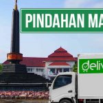 Mobil Deliveree di lokasi pindahan Malang dengan latar belakang monumen dan tulisan 'Pindahan Malang'.