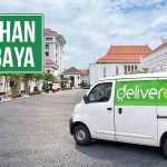Mobil Deliveree di area pindahan Surabaya dengan latar belakang bangunan dan tulisan 'Pindahan Surabaya'.