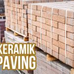 Tumpukan keramik dan paving batu yang terikat rapi di atas palet, menyoroti pengiriman material bangunan.