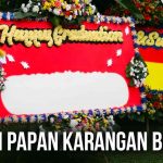 Papan karangan bunga merah dengan hiasan bunga berwarna-warni dan tulisan ucapan selamat, cocok untuk acara perayaan atau penghormatan.