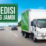 Truk ekspedisi melaju di jalan raya dengan papan petunjuk 'Ekspedisi Malang Jambi'.