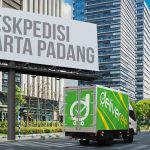 Truk Deliveree melintas di jalan perkotaan dengan papan reklame bertuliskan "Ekspedisi Jakarta Padang."