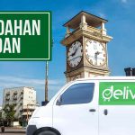 Mobil Deliveree di Medan dengan latar belakang menara jam, layanan pindahan tersedia.