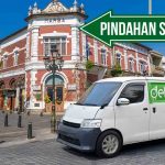 Mobil Deliveree parkir di depan bangunan bersejarah di Semarang dengan papan arah bertuliskan "Pindahan Semarang."