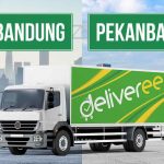 Truk Deliveree di tengah jalan dengan papan penunjuk arah 'Bandung' dan 'Pekanbaru' di latar belakang.