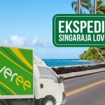 Gambar menunjukkan truk Deliveree di jalan dekat pantai dengan tanda yang mengarah ke "Ekspedisi Singaraja Lovina."