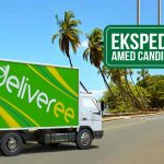 Gambar menunjukkan truk Deliveree di jalan dekat pantai dengan tanda yang mengarah ke "Ekspedisi Amed Candidasa."