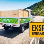 Truk ekspedisi Deliveree dengan peti kayu melaju di jalan pesisir menuju Jimbaran-Uluwatu.