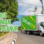 Truk Deliveree melintas di jalanan dengan Monumen Tugu Arjuna Gianyar terlihat di belakangnya. Terdapat tulisan “Ekspedisi Pengiriman Gianyar Sanur” di kiri atas.
