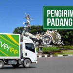 Truk Deliveree melewati jalan raya di belakangnya terdapat Patung Satria Gatotkaca di Bali, terdapat tulisan di kanan atas “Pengiriman Bali Padang Hemat”.