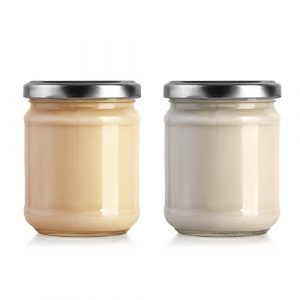 Dua toples kaca dengan tutup logam berisi krim berwarna krem dan putih.