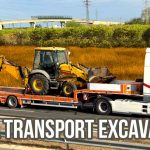Truk trailer membawa excavator di jalan tol.